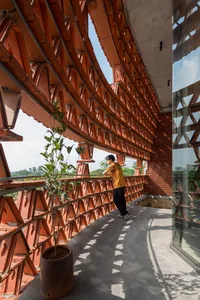 A modern terrace space featuring red brick concrete roof structures and a person leaning on a railing.
