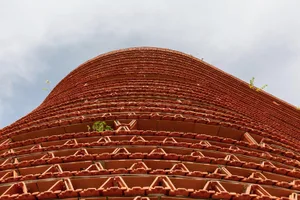 Detail of a curved brick roof with greenery growing through the gaps.