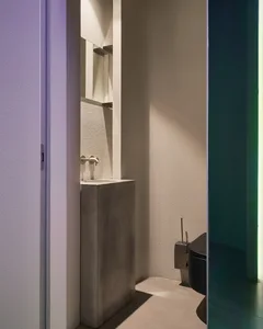 A minimalist concrete bathroom with a modern sink and toilet.