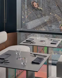 Modern restaurant interior with glass, concrete, and metal elements.