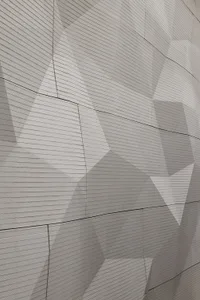 Modern architectural facade featuring a textured concrete surface with geometric patterns.