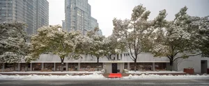 Modern exterior of a restaurant covered with snow, featuring wooden accents and concrete structures.
