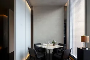 A minimalist restaurant interior featuring metallic accents, glass elements, and a minimalist design with concrete walls.