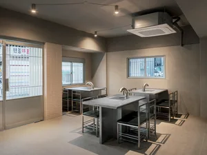 Industrial-style commercial kitchen with metal counters and stools.