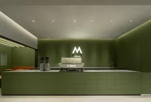 A modern cafe counter with green tiles and white espresso machine.