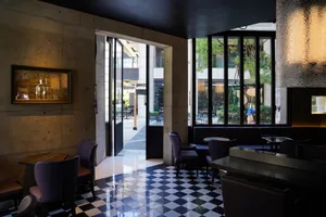 Modern interior of a restaurant with concrete walls, glass walls, and leather furniture.