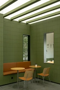 Indoor cafe space with green tile walls and wooden furniture.