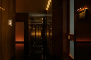 A minimalist hotel corridor with wooden walls and warm lighting, showcasing modern design elements.