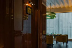 Modern restaurant interior with bold green lighting and black chairs.
