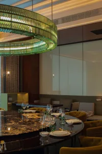 Modern restaurant interior with a large marble table and contemporary lighting fixtures.