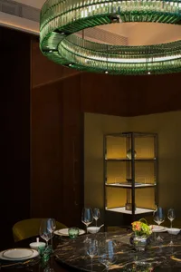 Modern interior design featuring a dining room with marble table, glass chandelier, and stainless steel accents.