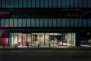 A modern storefront at night with glass walls and interior lighting.