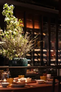 Floral arrangement in a ceramic vase on a table in a restaurant setting.