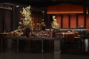 A modern restaurant bar features wooden furniture and dark metal fixtures.