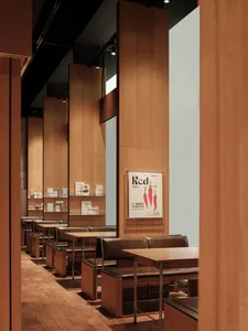 A detailed view of a modern restaurant dining room with cork floor, wood-paneled walls, and bookshelves filled with books.