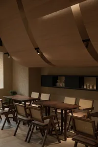 A modern restaurant with wooden furniture and a curved wooden ceiling.
