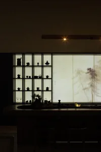 A modern tea room with shelves containing various teapots, glasses, and jars.