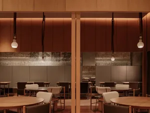 A restaurant interior with wooden ceiling features and cement walls.