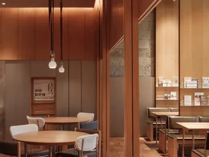 Modern cafe interior featuring tables, chairs, and bookshelf with books and magazines