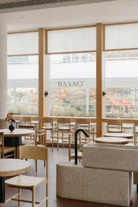 Contemporary restaurant interior featuring wooden tables and chairs, stone sink, and minimalist design.