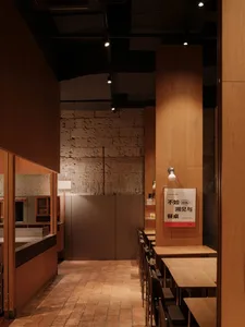 A modern restaurant interior featuring wooden elements and a stone wall.