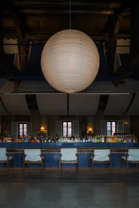 A dimly lit bar with a large spherical light fixture and blue-tiled walls.
