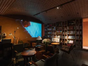 A cozy library room with brick walls and a projection screen.