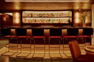 A modern bar with a marble countertop and stools.