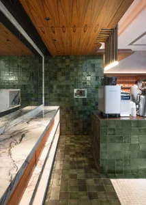 A modern cafe interior featuring green tiled walls and marble countertops.