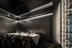 A sleek, modern restaurant dining room with metallic texture walls, illuminated by subtle LED lighting and featuring a dining