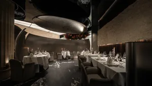 Modern restaurant interior with metallic ceiling, wood walls, and fabric seating.