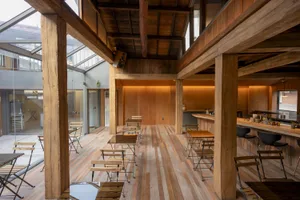 A wooden coffee shop interior with exposed beams and floor-to-ceiling glass windows.