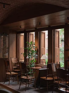 Industrial-style restaurant interior with wooden tables, chairs, and potted plants.