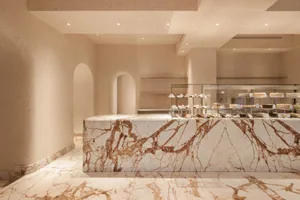 A modern retail shop interior featuring marble finishes and baked goods on display.