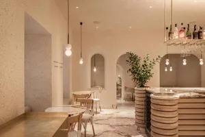 Interior view of a modern restaurant with concrete walls, marble countertops, and wooden furnishings.
