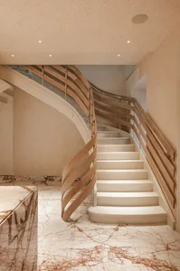 A modern white marble staircase with wooden railings in a well-lit interior.