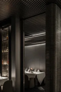 Modern restaurant dining room with metallic elements and white tablecloth.