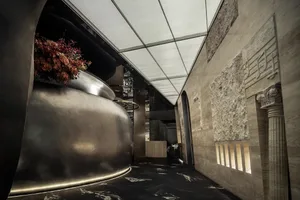 A modern industrial restaurant with a curved, metallic wall and decorative flowers.