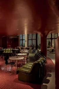 A sleek, modern industrial restaurant bar featuring green leather sofas and black metal furniture.
