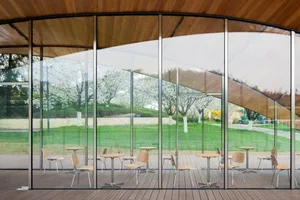 View of outdoor seating area through large glass windows.