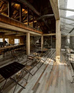 An industrial-style restaurant interior with exposed wooden beams and rustic furniture.