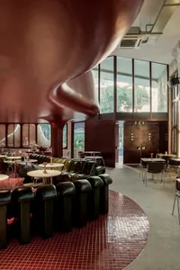Modern cafe interior featuring metallic finishes, leather cushions, and red checkered tile floor.