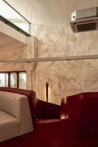 Modern interior design featuring textured stucco walls and a red geometric cube.