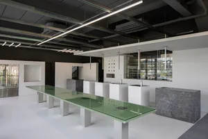 A modern, minimalist workspace featuring concrete and glass elements.