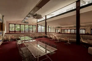 Modern restaurant interior featuring transparent tables and upholstered seating.
