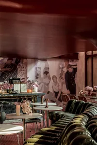 A modern restaurant interior with white tables, flower arrangements, and a leather sofa.