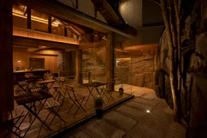 A wooden rock-themed restaurant bathroom with exposed wooden beams and walls covered in rock textures