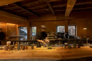 A modern industrial coffee shop with a wooden counter, featuring sleek design elements and minimalist decor.