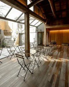 A modern industrial restaurant interior with wooden furniture and a stone staircase.