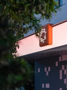 Modern building exterior with signage featuring a geometric design and orange and pink colors.